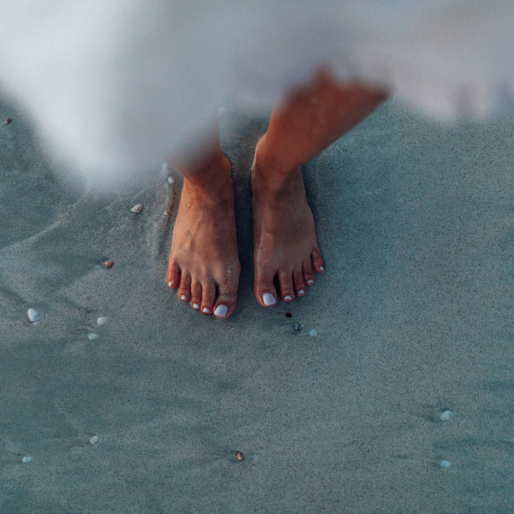 Gepflegte Füße im Sand am Strand – sommerliche Pedicure mit natürlichem Look für entspannte Urlaubsmomente.